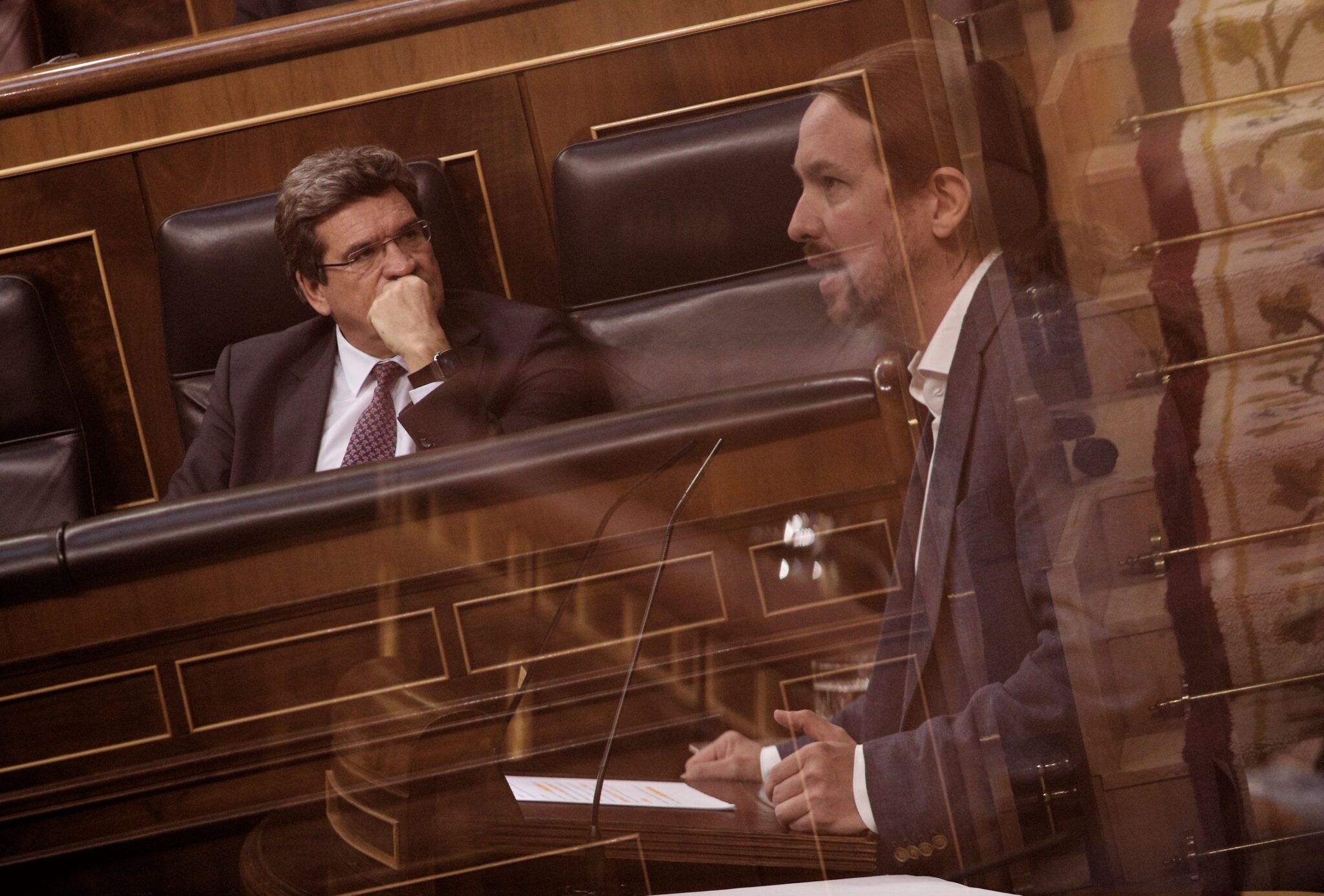 José Luis Escrivá escucha a Pablo Iglesias durante un pleno en el Congreso, en el año 2020.