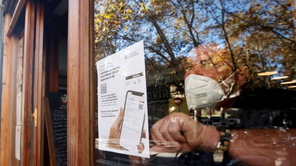 Un empresario coloca un cartel en Cataluña informando de la exigencia del pasaporte covid para acceder al local.