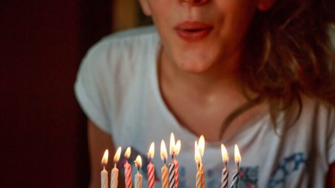 Mujer sosteniendo una tarta de cumpleaños mientras sopla las velas