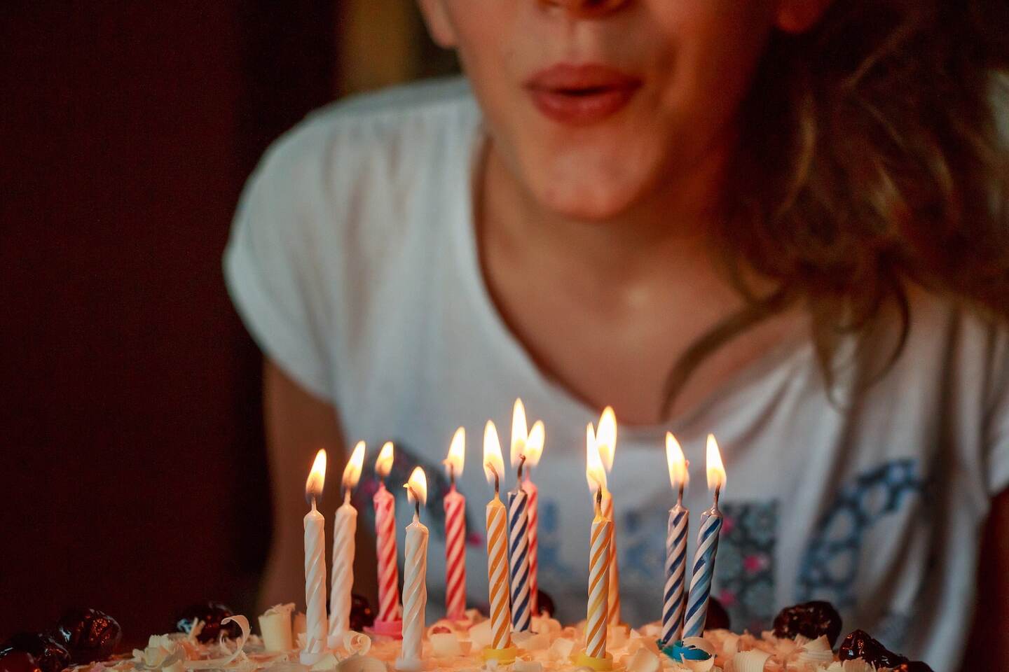 Mujer sosteniendo una tarta de cumpleaños mientras sopla las velas