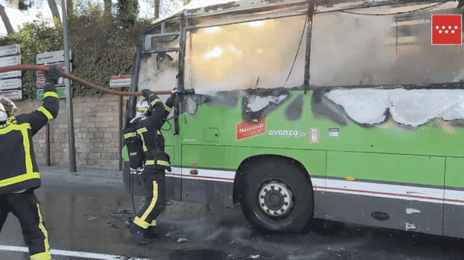 Autobús del casco urbano de Pozuelo incendiado, mientras lo bomberos intentan frenar el fuego