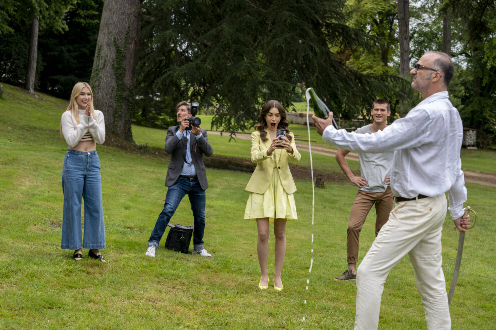 (De izquierda a derecha) Camille Razat como Camille, Guillaume Clemencin como Liberation Reporter, Lily Collins como Emily, Victor Meutelet como Timothée, Christophe Guybet como Gerard en el episodio 2x08 de 'Emily en París.'