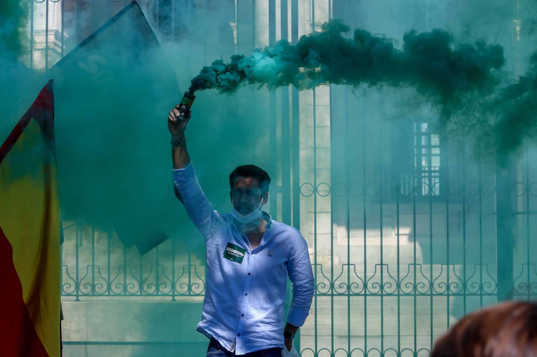 Un hombre lanza humo de color verde en una manifestación convocada por Solidaridad, el sindicato adscrito a Vox.