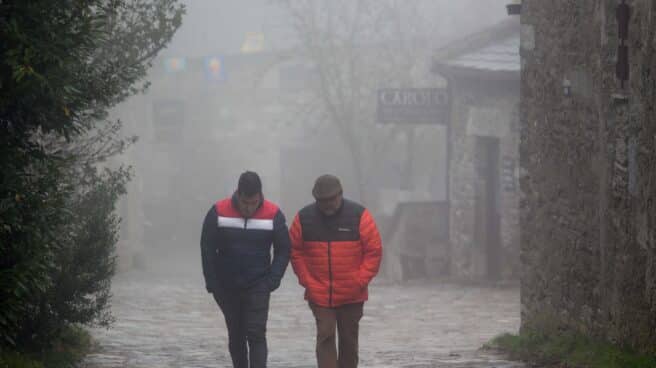 Dos hombres caminan entre la niebla en la aldea prerromana de O Cebreiro, Concello de Pedrafita do Cebreiro, Lugo, Galicia (España)