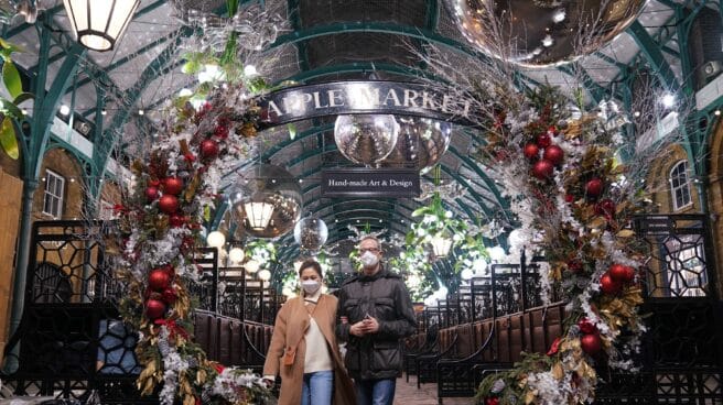Reino Unido, Londres: la gente camina debajo de las decoraciones en el mercado navideño de Covent Garden, donde han entrado en vigor nuevas restricciones para frenar la propagación de la variante Omicron del coronavirus.