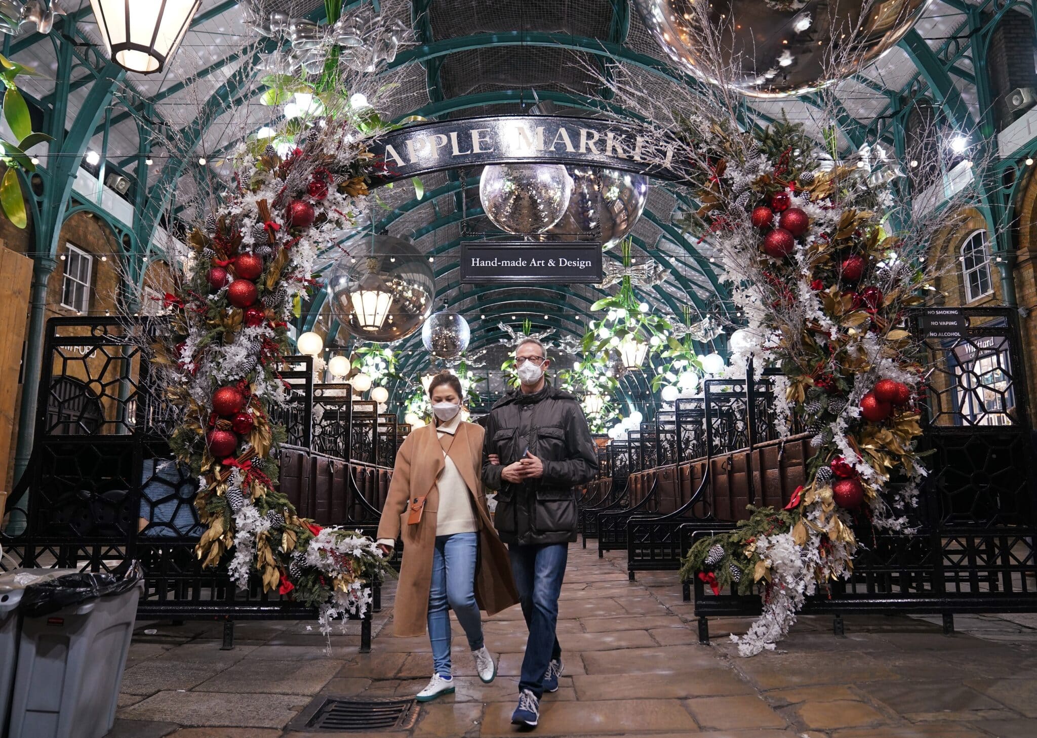 Reino Unido, Londres: la gente camina debajo de las decoraciones en el mercado navideño de Covent Garden, donde han entrado en vigor nuevas restricciones para frenar la propagación de la variante Omicron del coronavirus.
