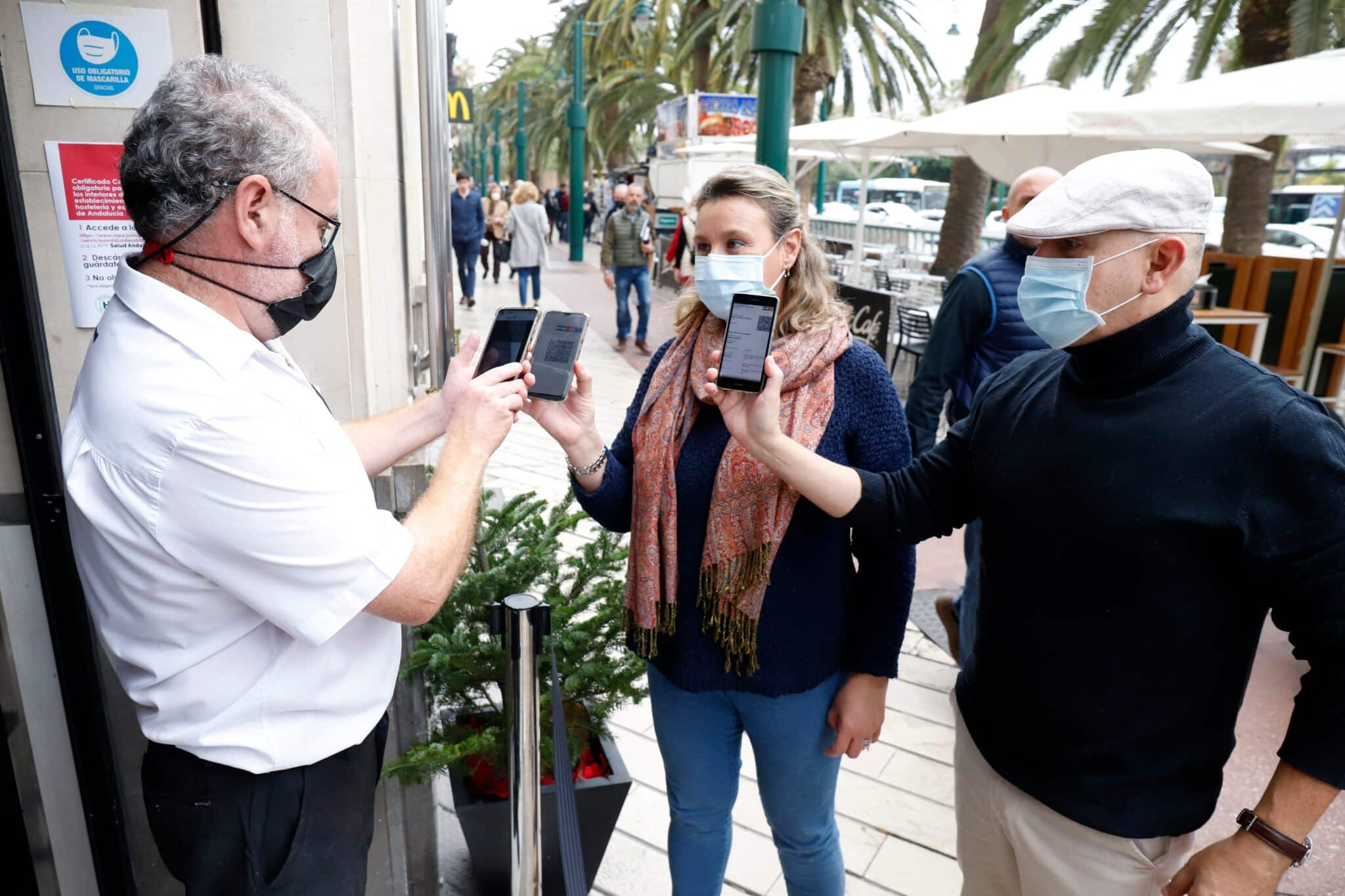 Un camarero pide certificado a los clientes en la puerta de un bar durante el primer día de petición de Certificados Covid-19