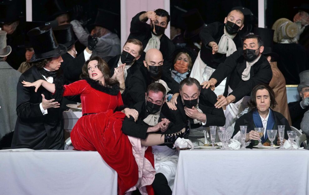 escena de la bohéme con Ruth Iniesta (Musetta), Lucas Meachem (Marcello), Joan Martín-Royo (Schaunard), Coro Titular del Teatro Real y actores