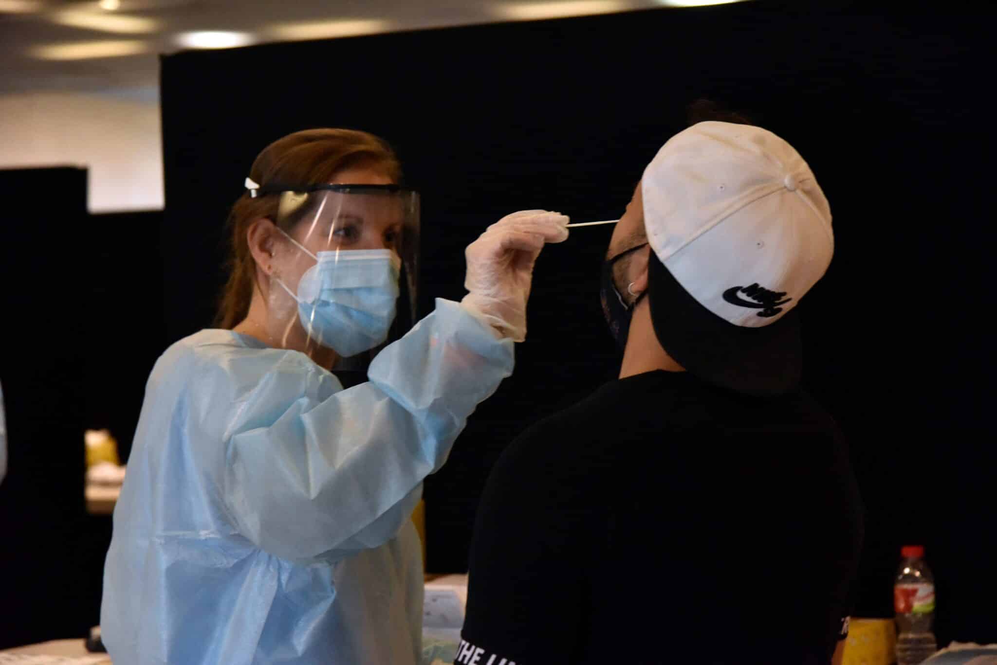 Una trabajadora sanitaria realiza un test de antígenos a un joven.