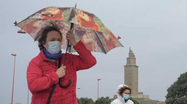 Varias personas pasean en el Paseo Marítimo durante una ciclogénesis explosiva en A Coruña