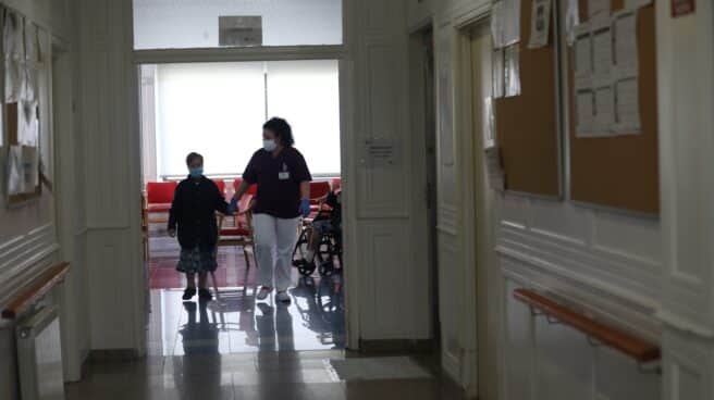 Una gerocultura coge de la mano a una residente en una residencia de Madrid.