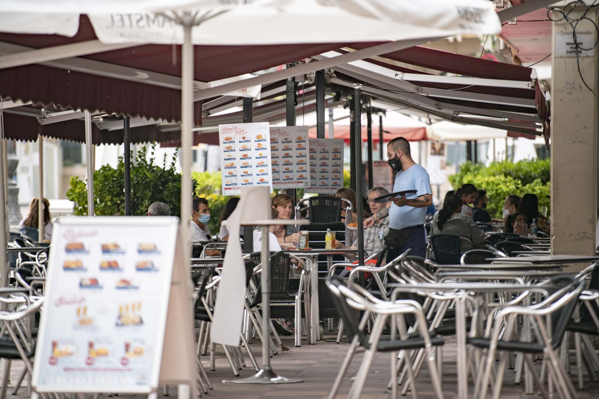 Un camarero atiende a varios clientes en la terraza de un bar en la Plaza Mayor de Ciudad Real (Castilla-La Mancha)