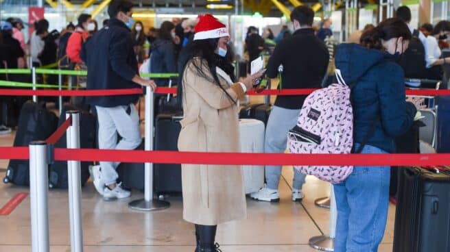 Una mujer con un gorro de Papá Noel hace cola en el aeropuerto de Barajas, este jueves 23 de diciembre.