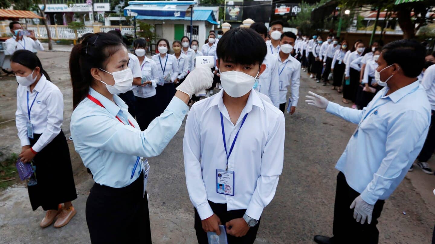 Una profesora toma la temperatura a un alumno en Camboya