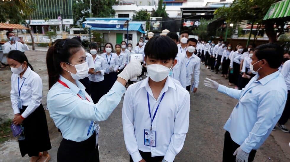 Una profesora toma la temperatura a un alumno en Camboya