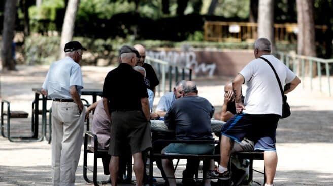 Varios pensionistas juegan al dominó en un parque de Madrid.