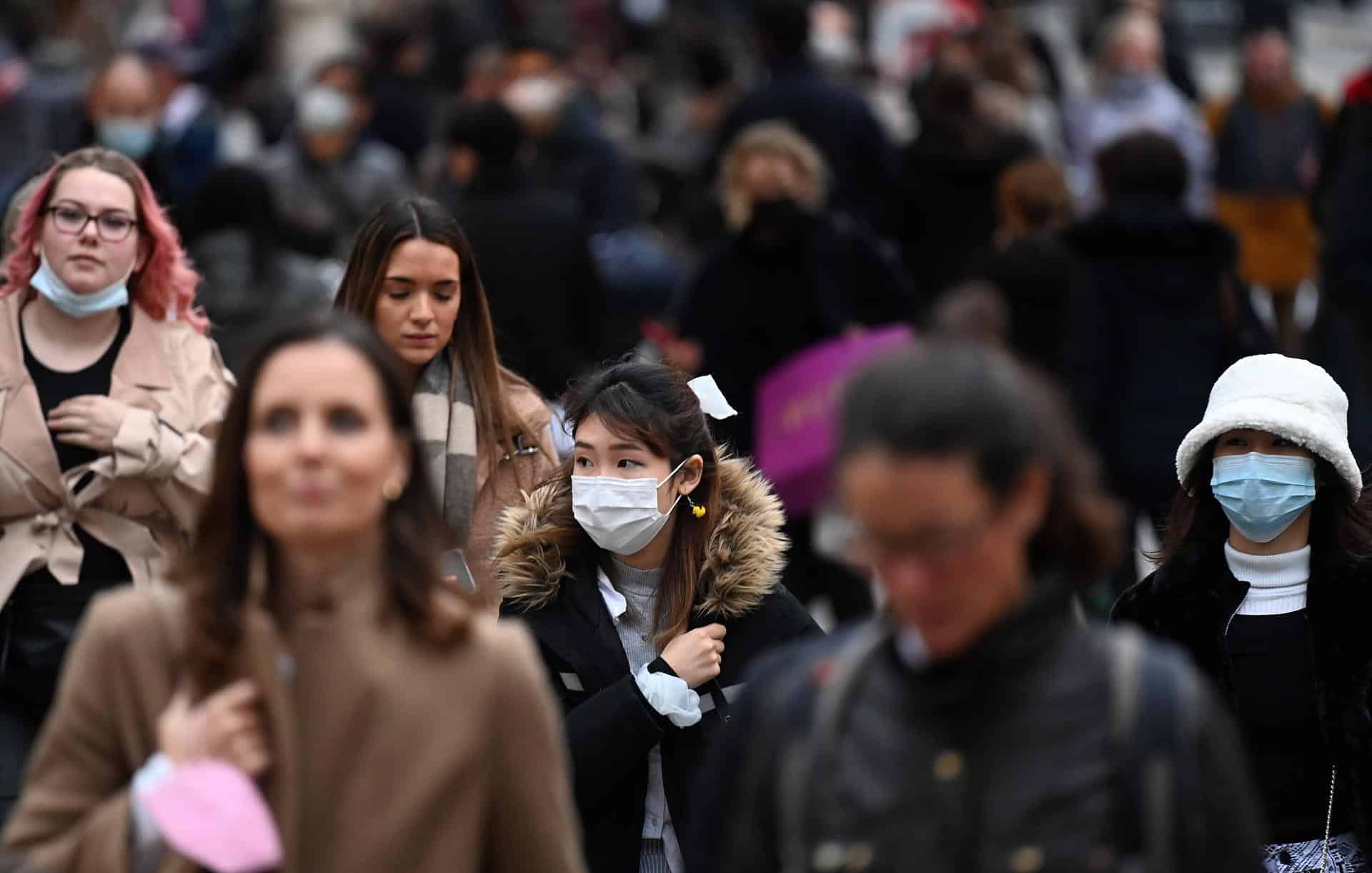 Personas caminan por la calle con y sin mascarilla, ante la expansión de la variante ómicron.