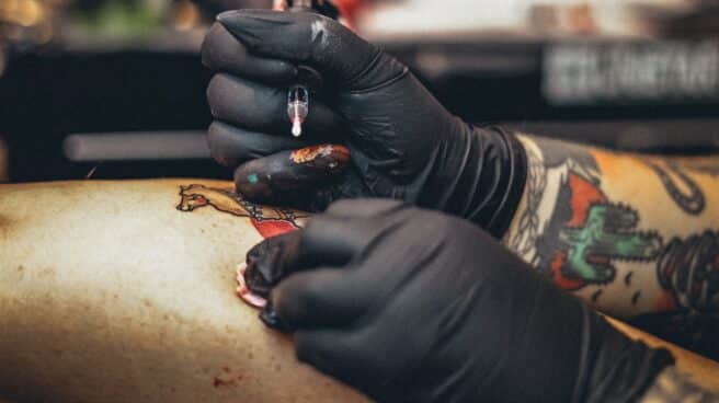Un tatuador realizando un tatuaje.