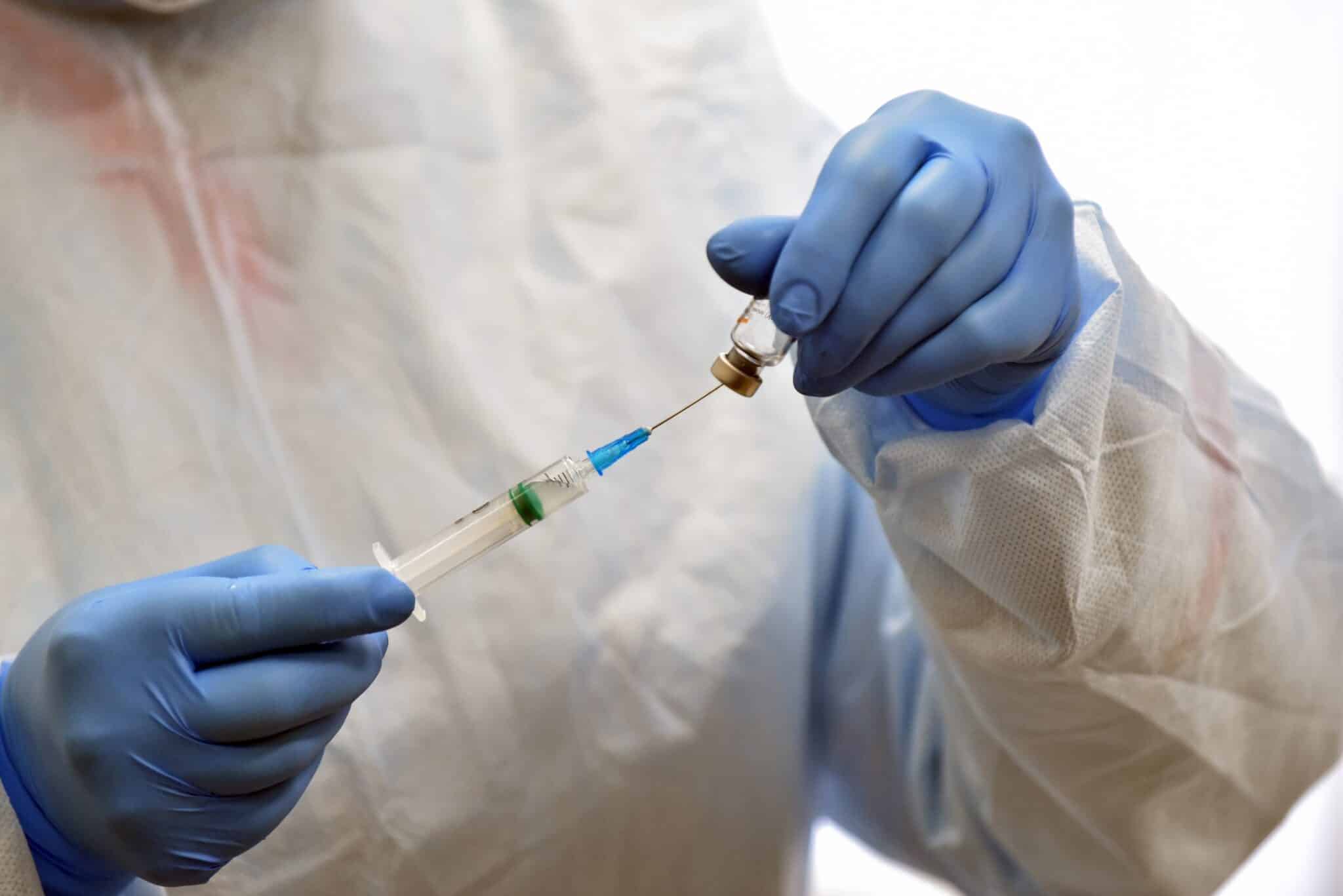 Un sanitario descarga en una jeringuilla un vial de una vacuna frente al covid.