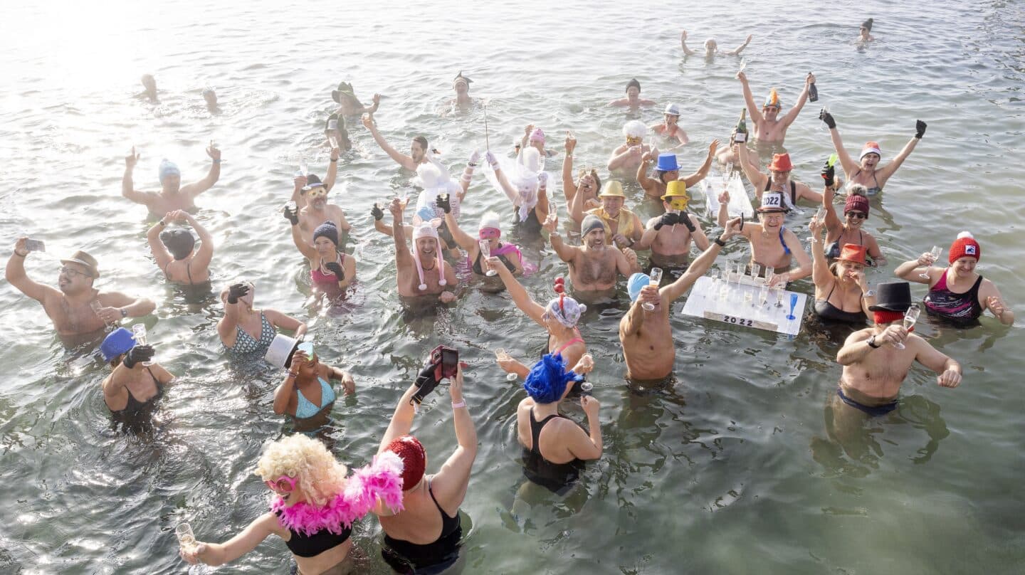 Las personas brindan con champán mientras se bañan en el agua fría durante el tradicional día de Año Nuevo nadando en el lago de Ginebra en el 'Bains des Paquis'