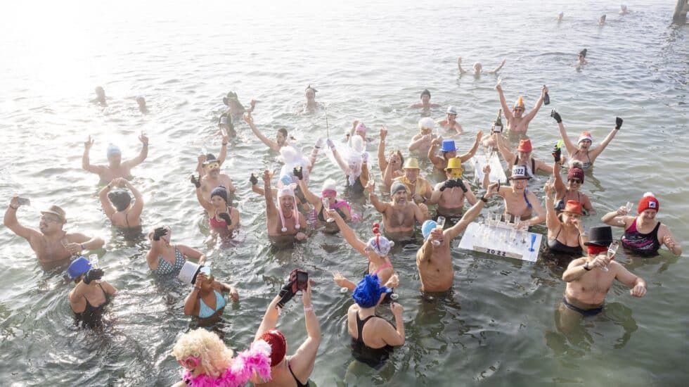 Las personas brindan con champán mientras se bañan en el agua fría durante el tradicional día de Año Nuevo nadando en el lago de Ginebra en el 'Bains des Paquis'