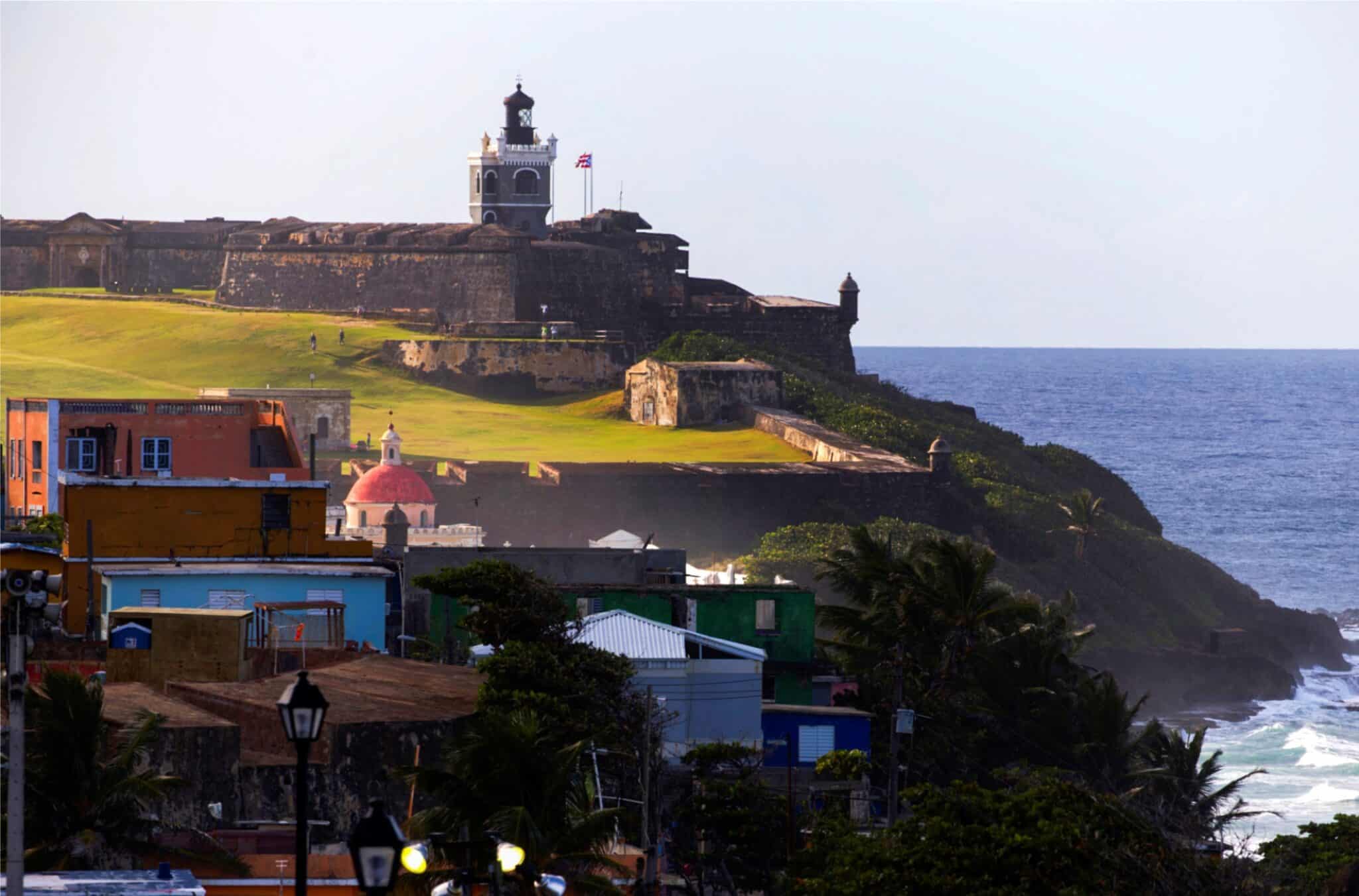 Fotografía donde se aprecia una parte del barrio La Perla y al fondo el castillo de San Felipe del Morro, conocido simplemente como El Morro, en el Viejo San Juan