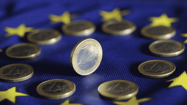 El euro cumple 20 años en circulación con la mirada puesta en la nueva era digital Moneda de Euro en una bandera de Europa