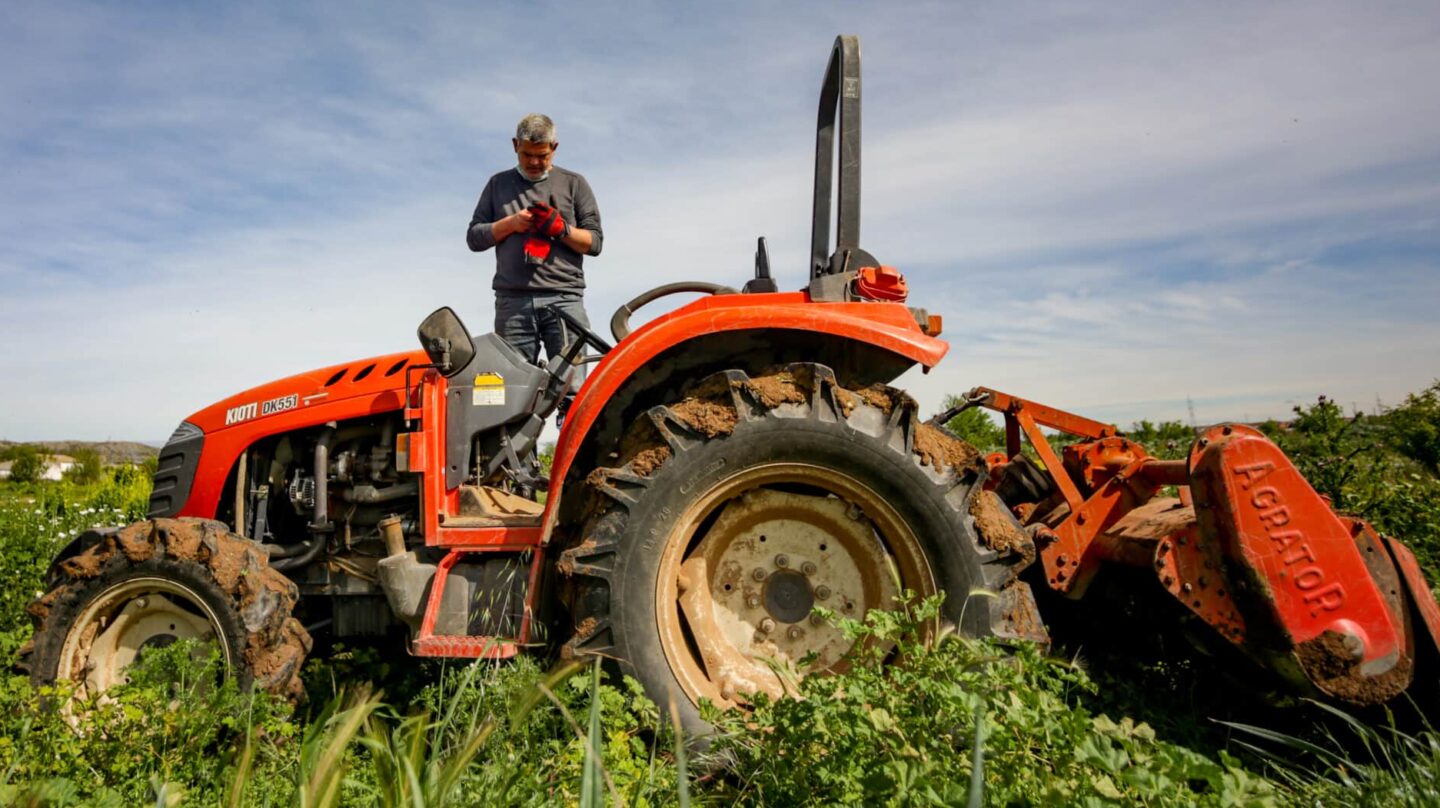 Un hombre siega la tierra del campo perteneciente a la huerta ecológica de Ecosecha, en Velilla de San Antonio, Madrid.