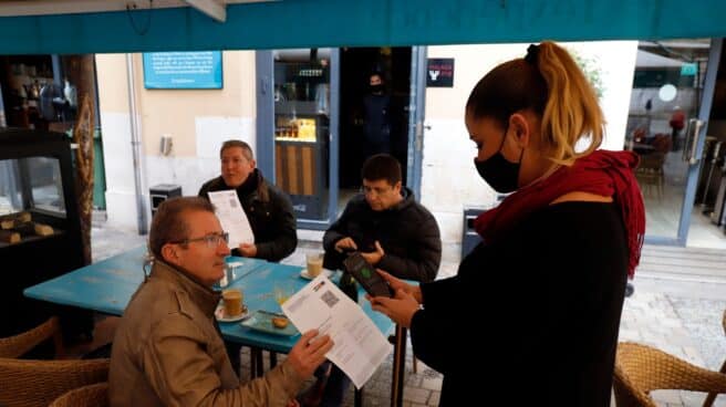 Una camarera pide certificado a los clientes en una mesa en la terraza de un bar durante el primer día de petición de Certificados Covid