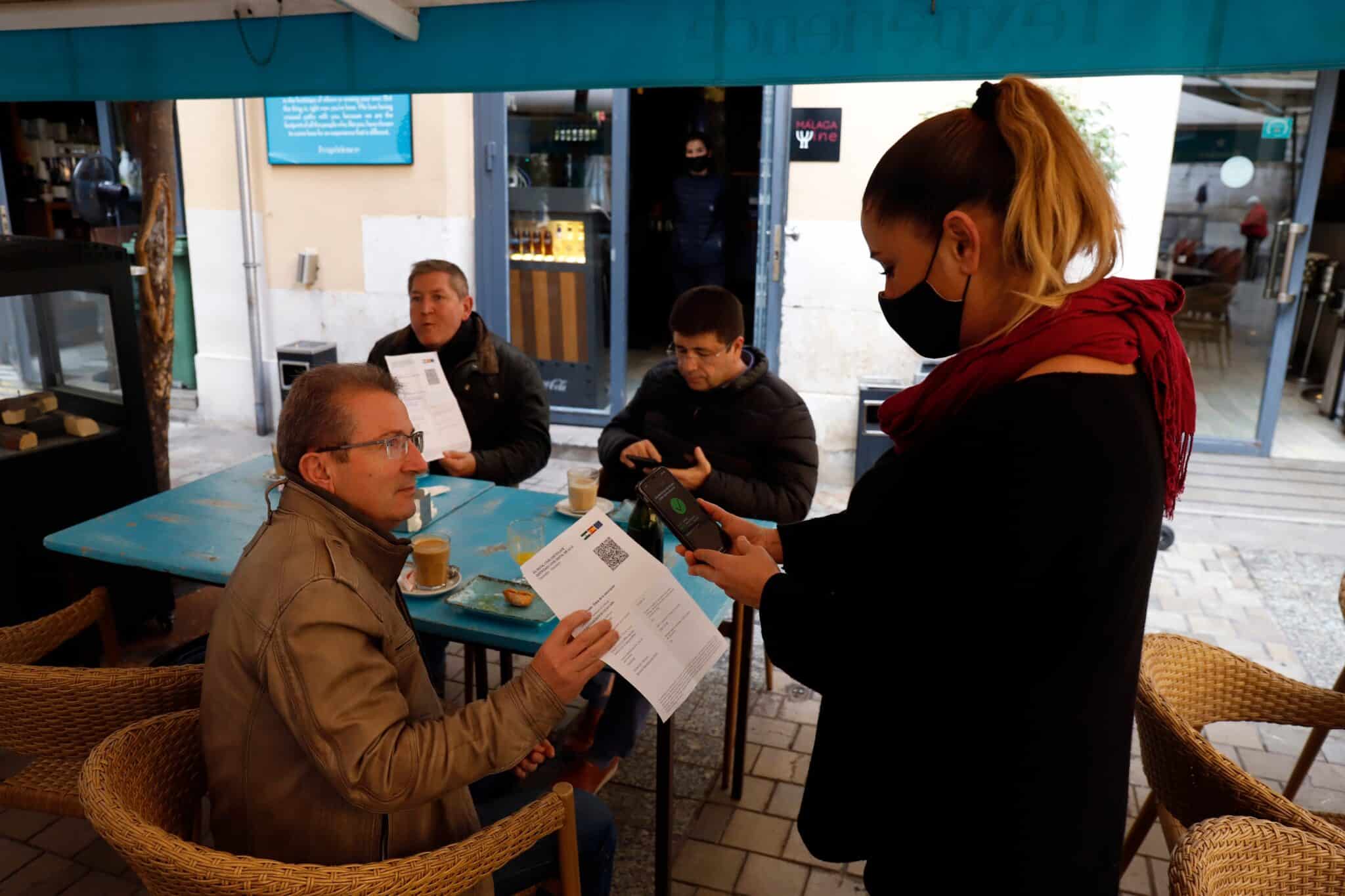 Una camarera pide certificado a los clientes en una mesa en la terraza de un bar durante el primer día de petición de Certificados Covid