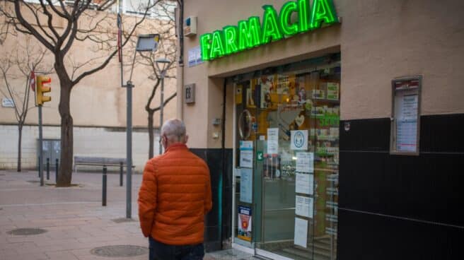 Una persona pasa al lado de una farmacia.