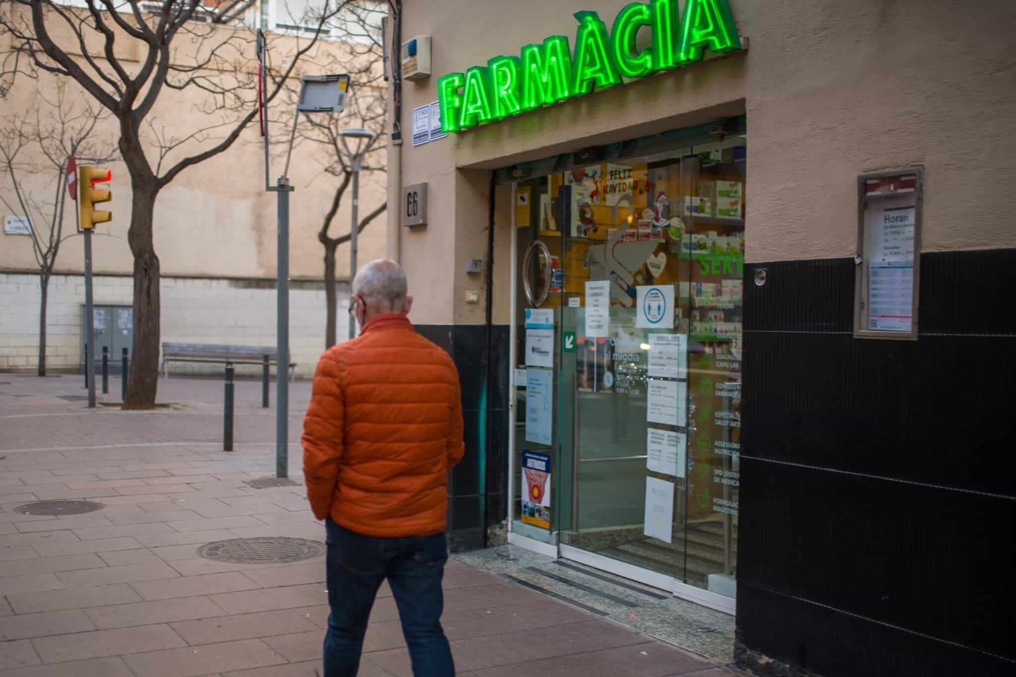 Una persona pasa al lado de una farmacia.