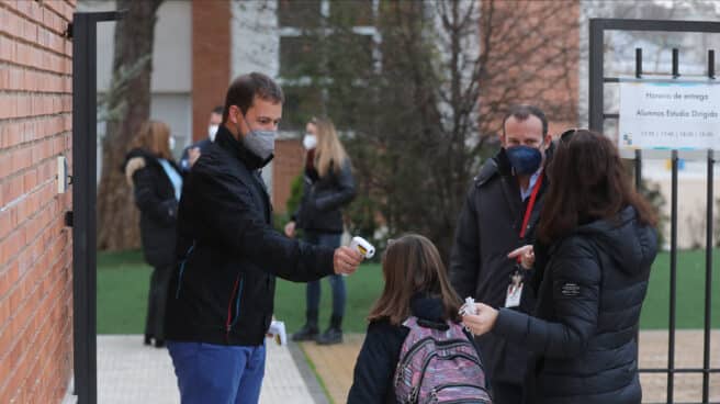 Un trabajador toma la temperatura a un niño a su llegada al primer día de clase presencial tras la Navidad