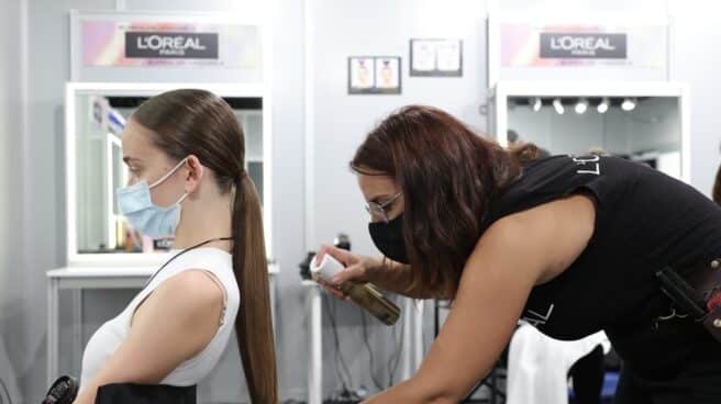 Una peluquera peina a una modelo para un desfile en la Mercedes Benz Fashion Week, en Madrid.