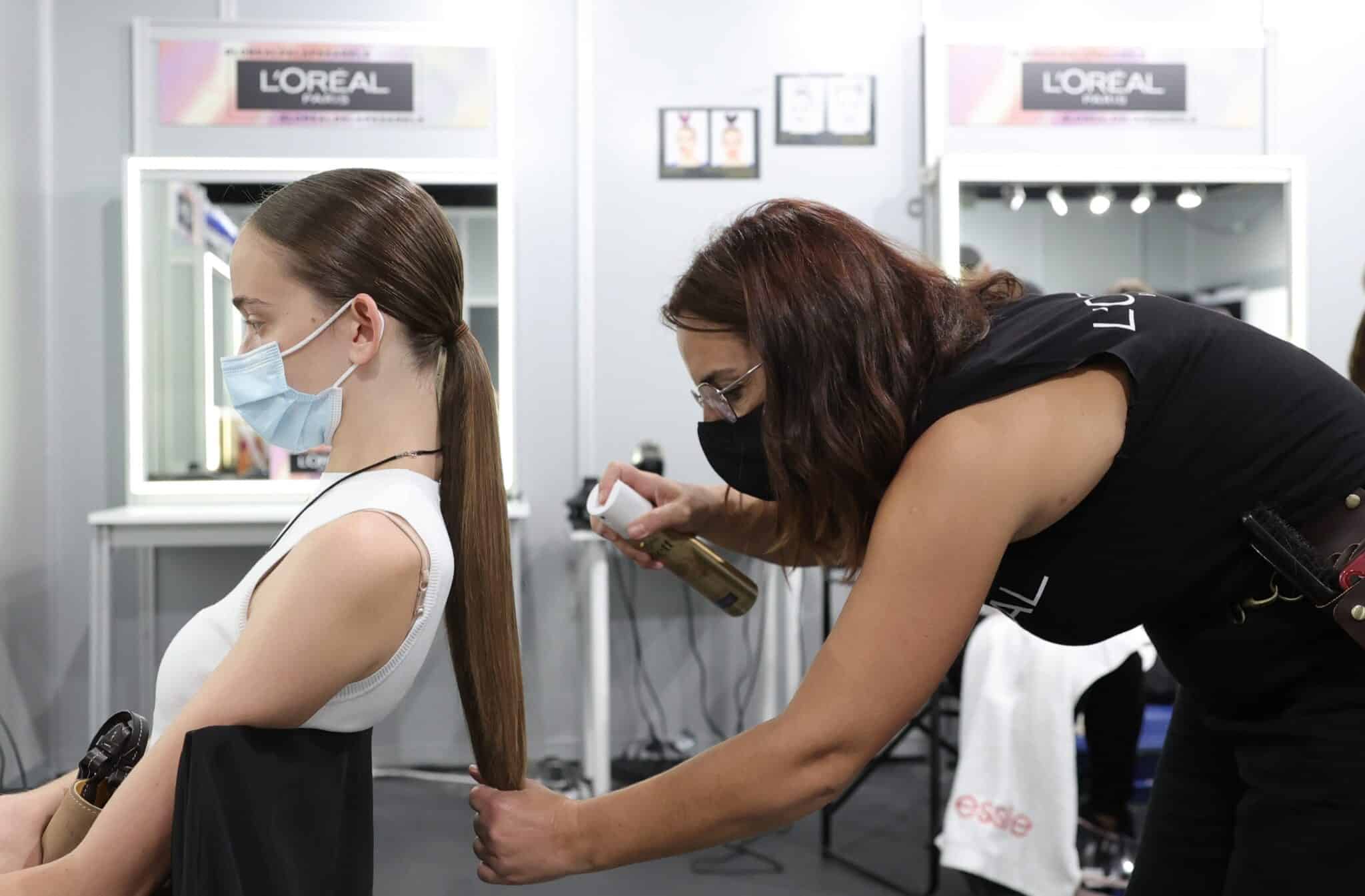 Una peluquera peina a una modelo para un desfile en la Mercedes Benz Fashion Week, en Madrid.