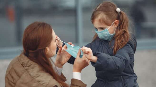 Niña colocando la mascarilla a su madre en tiempos de Covid