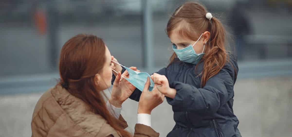 Niña colocando la mascarilla a su madre en tiempos de Covid