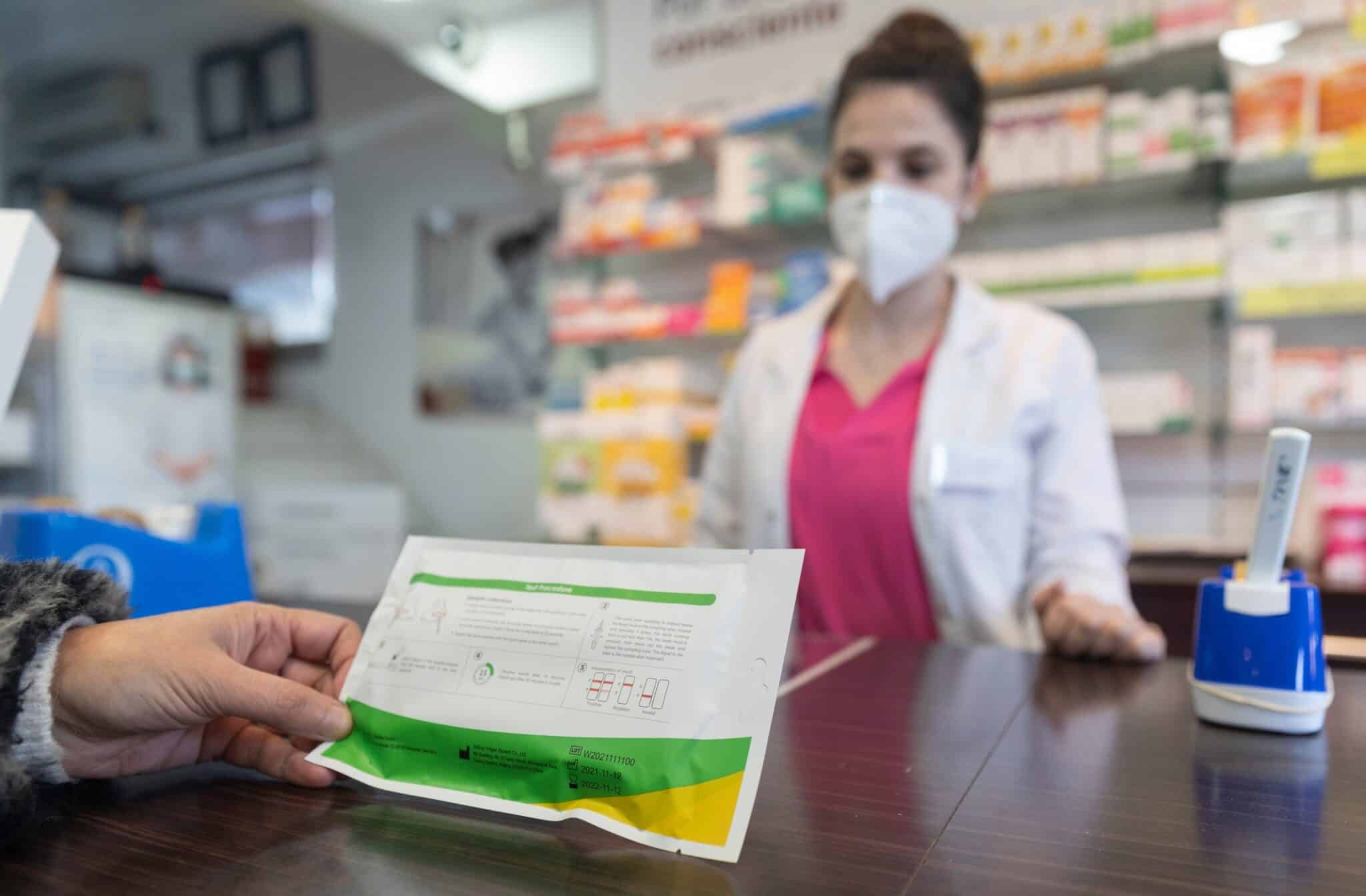 Una farmacéutica vende un test de antígenos.