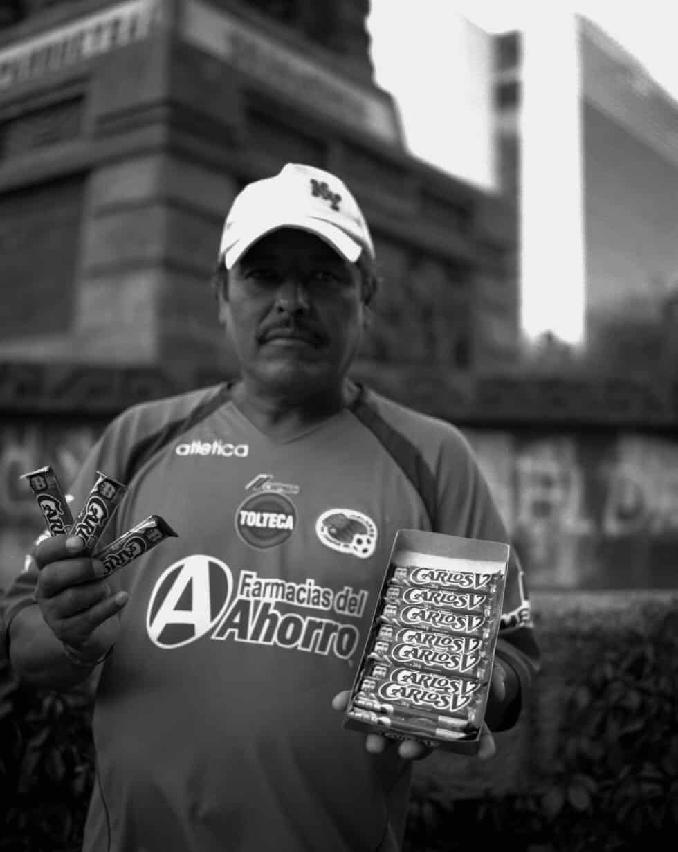 Vendedor ambulante de chocolates Carlos V junto al monumento a Cuauhtémoc, cruce de Reforma e Insurgentes, Ciudad de México