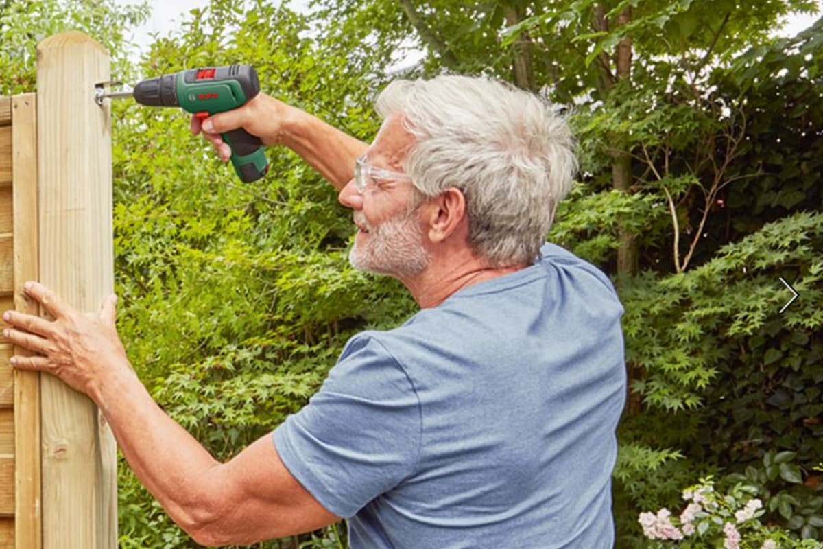 Hombre con el taladro bosch haciendo un agujero en madera