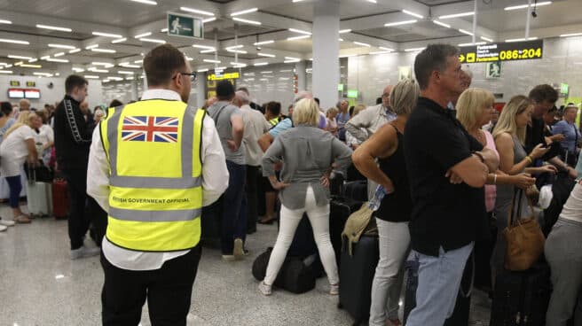 Un guarda de seguridad británico observa a los turistas que hacen cola en el aeropuerto de Palma de Mallorca (Baleares).