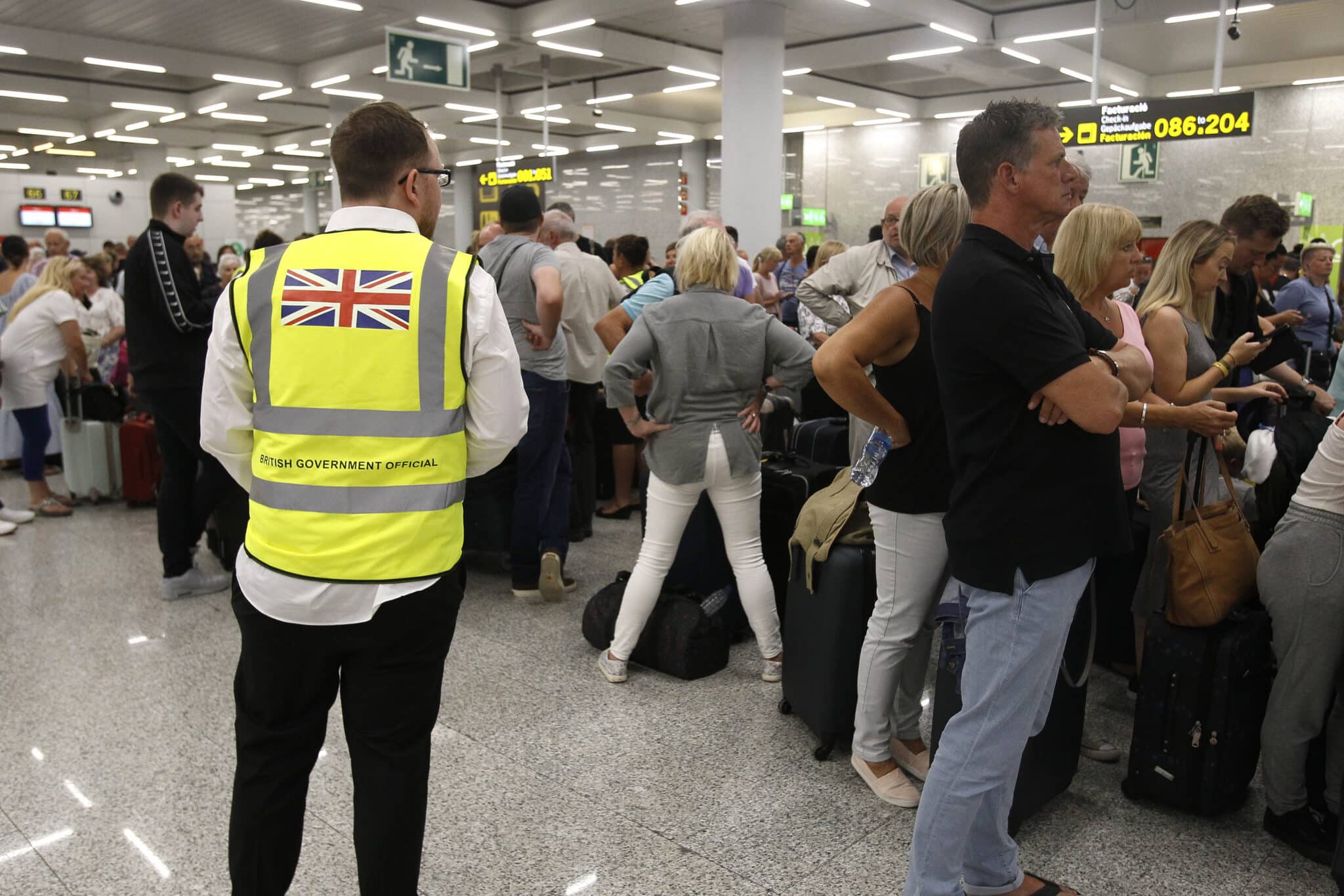 Un guarda de seguridad británico observa a los turistas que hacen cola en el aeropuerto de Palma de Mallorca (Baleares).