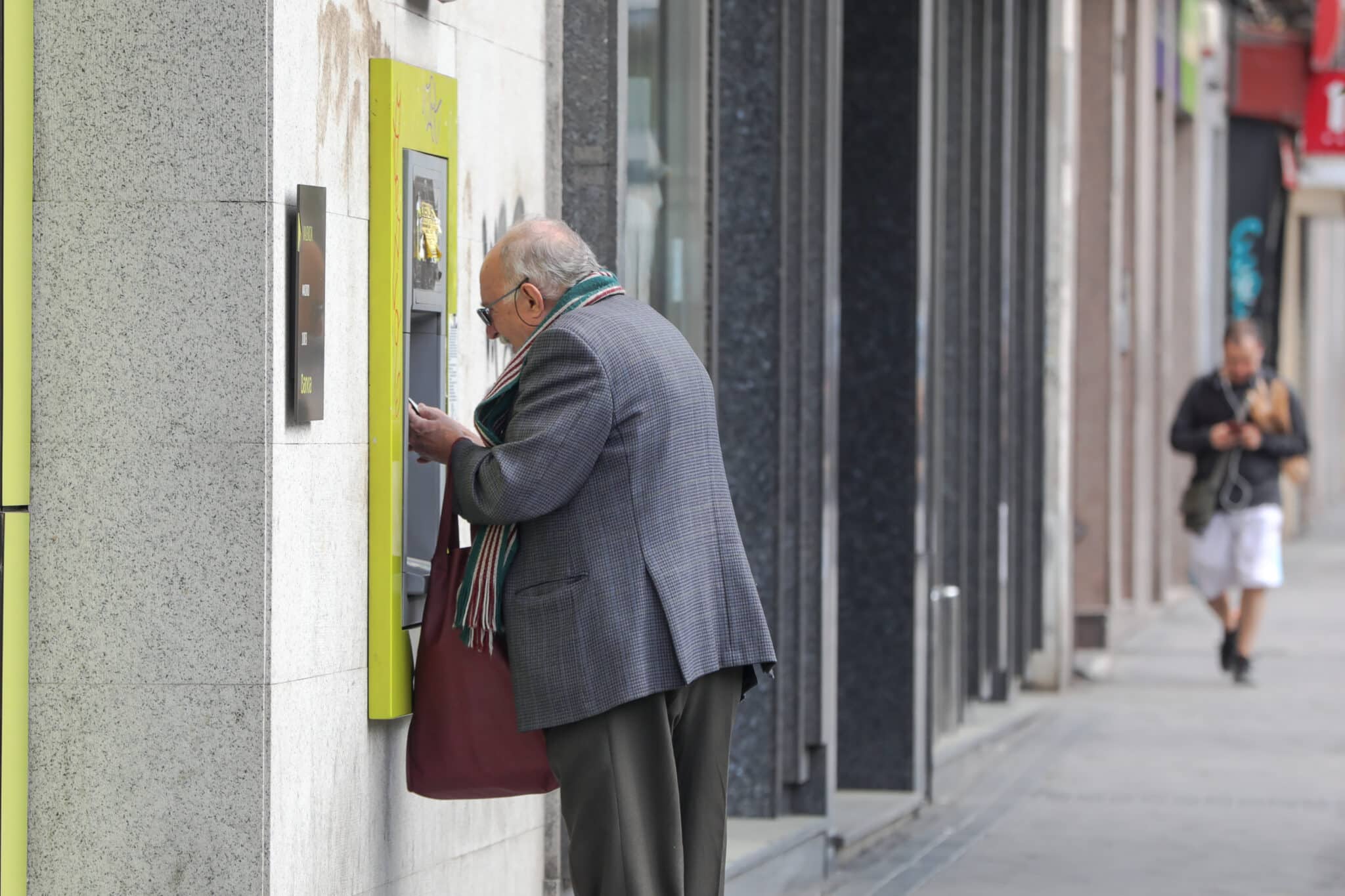 Un anciano saca dinero de un cajero