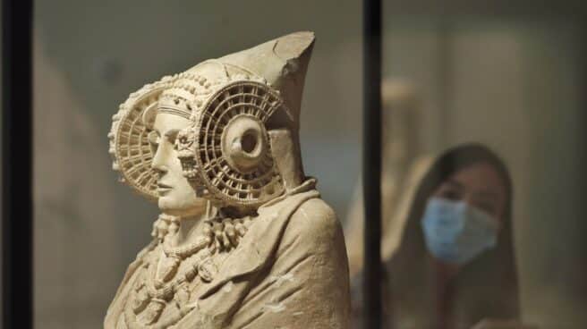 Una persona protegida con mascarilla observa la escultura de La Dama de Elche disponible en el Museo Arqueológico