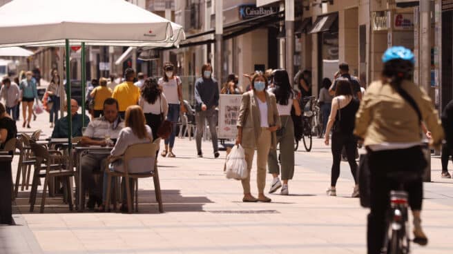 Personas paseando con mascarillas y sentadas en terrazas en una céntrica calle de Vitoria