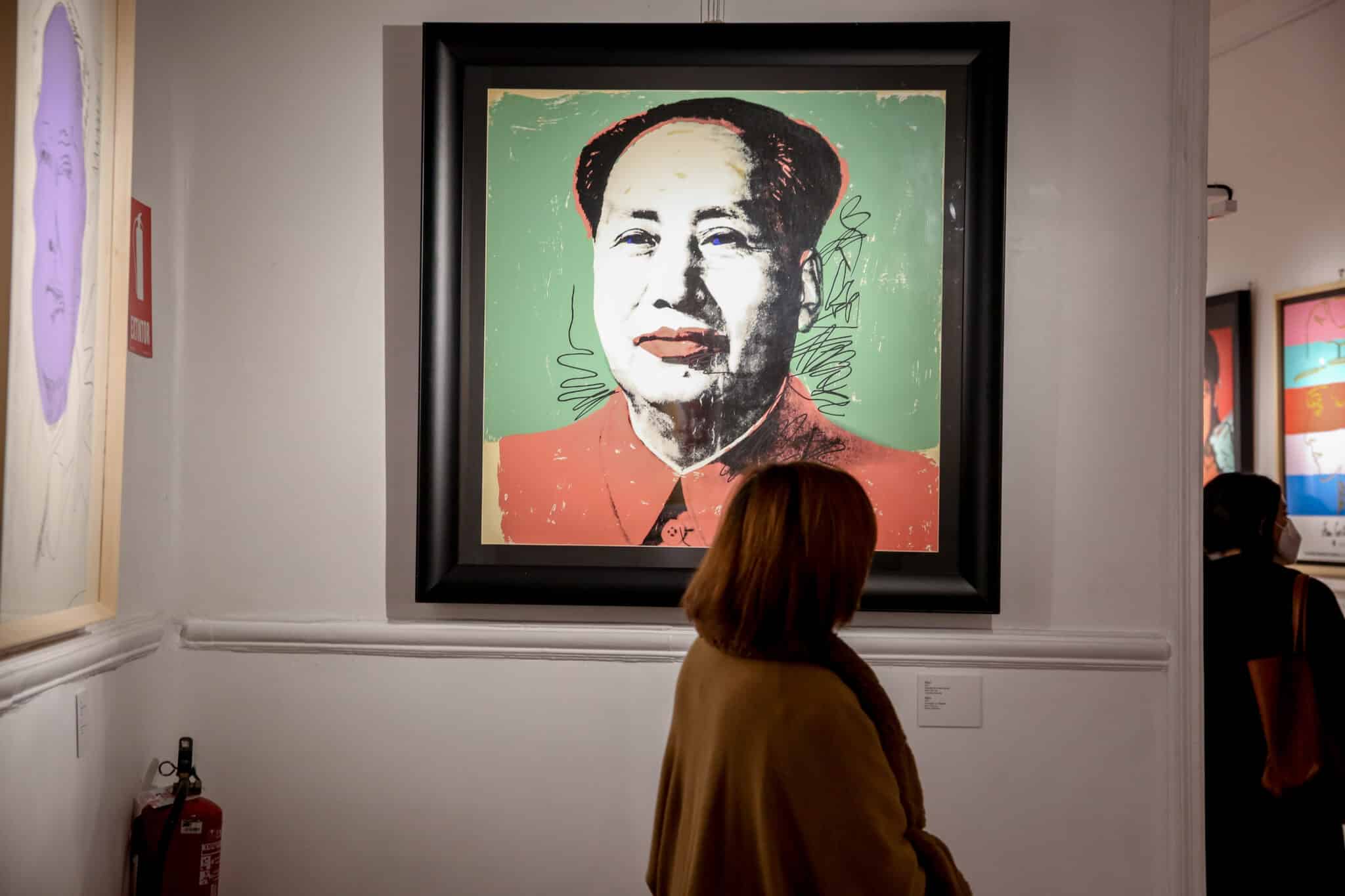 Una mujer, delante de un retrato de Mao Tse Tung, en la inauguración de la exposición 'ANDY WARHOL SUPER POP', en el Palacio de Santa Bárbara, a 11 de febrero de 2022, en Madrid (España). La muestra, de la compañía Next Exhibition, realiza un recorrido histórico y profesional del artista Andy Warhol, un viaje por la América de los años 1950, 1960 y 1970. Con la participación de Art Motors y el apoyo de la Cámara de Comercio Italiana, la exposición estará abierta al público del 12 de febrero al 5 de junio.