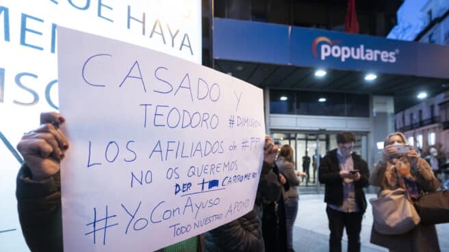 Un afiliado muestra un cartel en la sede de Génova del PP.