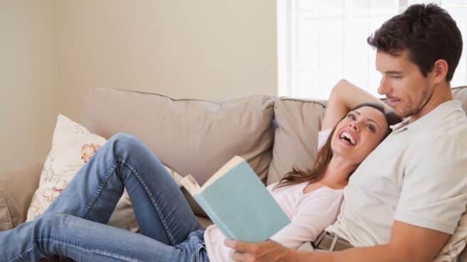 Pareja de hombre y mujer en un sofá leyendo un libro por San Valentín