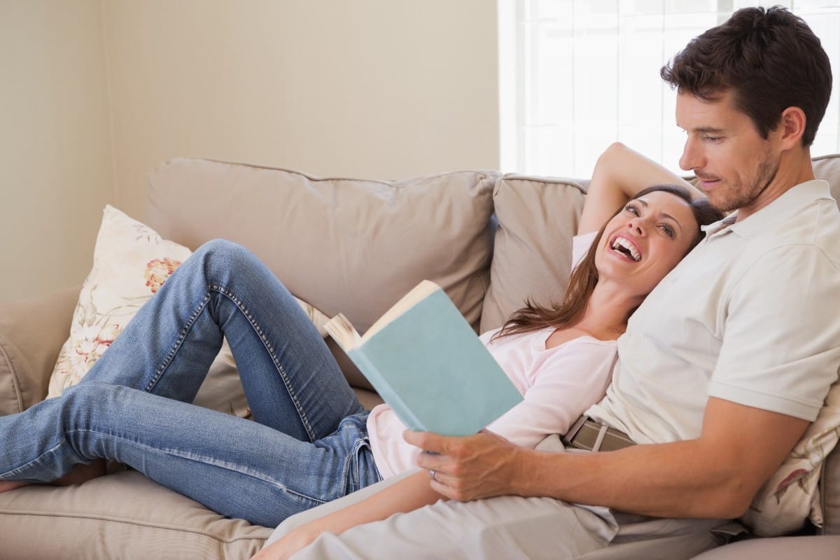 Pareja de hombre y mujer en un sofá leyendo un libro por San Valentín