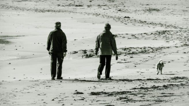 Una pareja de personas mayores camina por la playa